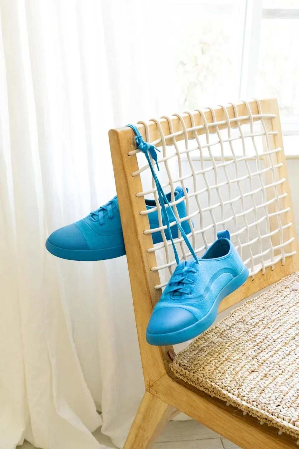 Blue Juntos shoes displayed beside a woven chair
